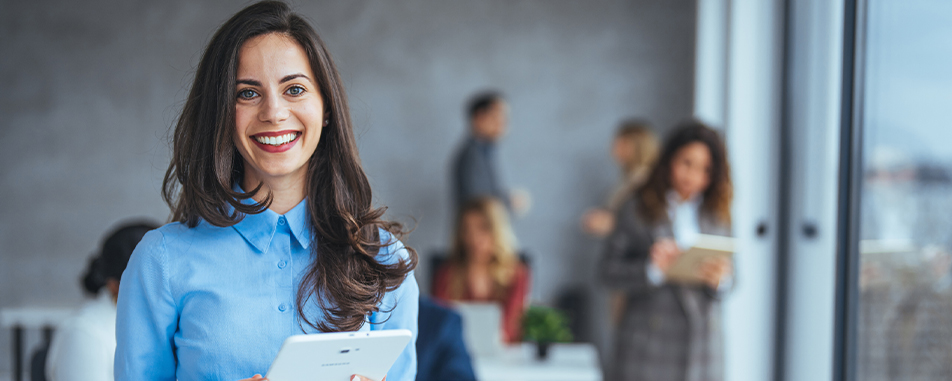 Smiling business professional holding a tablet in an office setting - www.purplecowinsurance.com